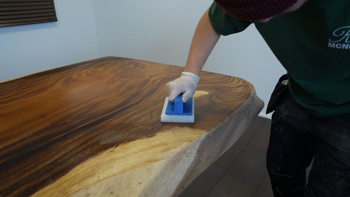 Person applying Rubio Monocoat wood finish to a wooden table using an application pad.